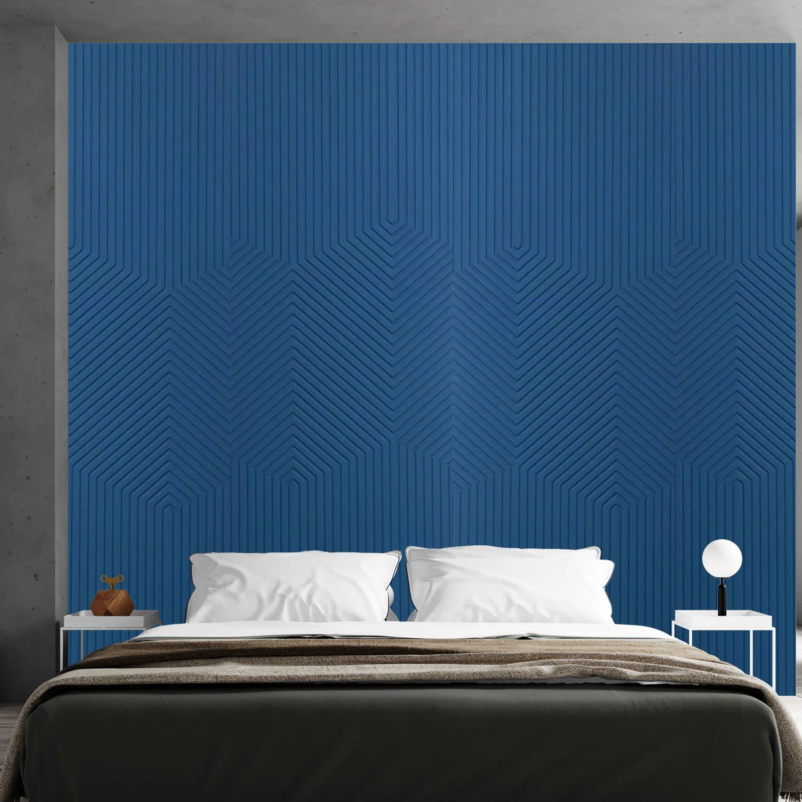 Deep blue chevron-relief panel wall behind a low bed with dark bedding
