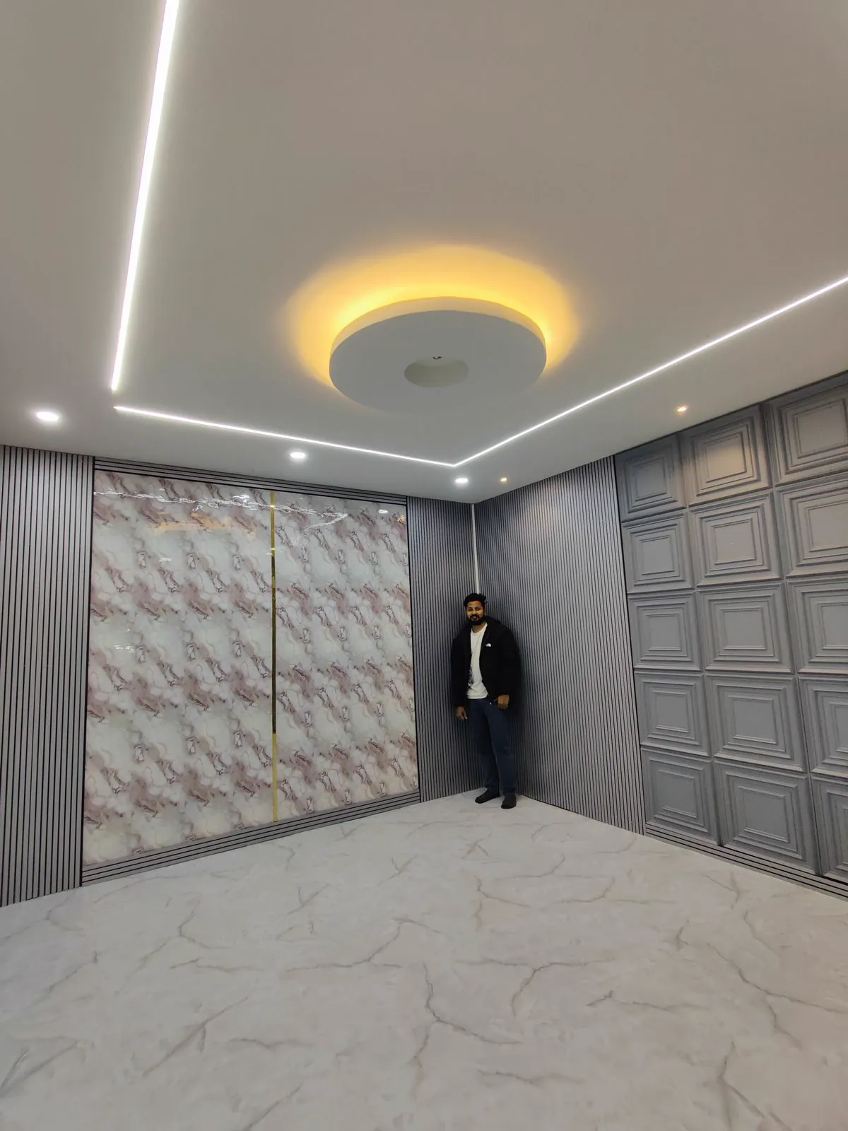 Room finished in printed marble sheet, grey flute and grey coffered panels, with a circular cove-lit false ceiling