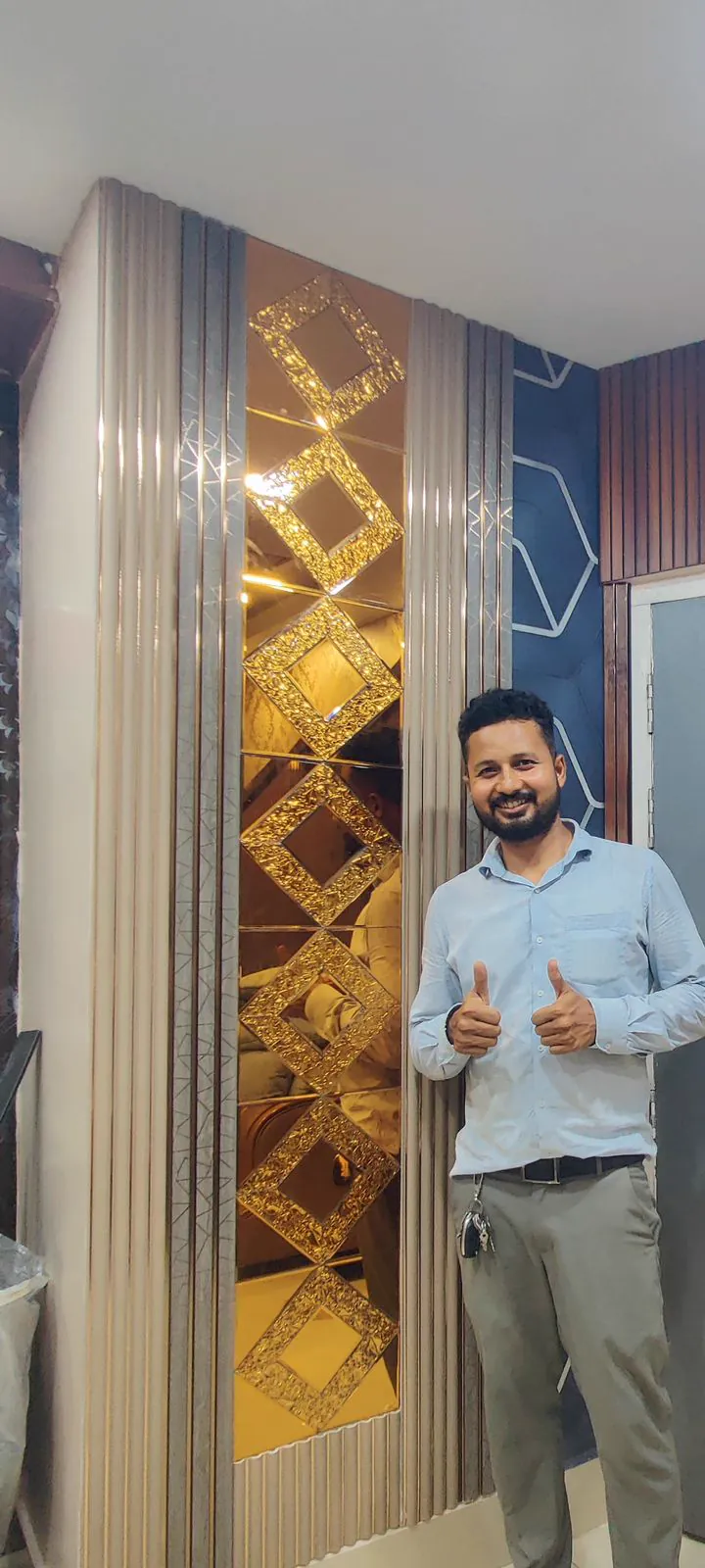 Gold diamond mirror mosaic column framed by fluted panels, a member of the Wow Interior team standing beside it