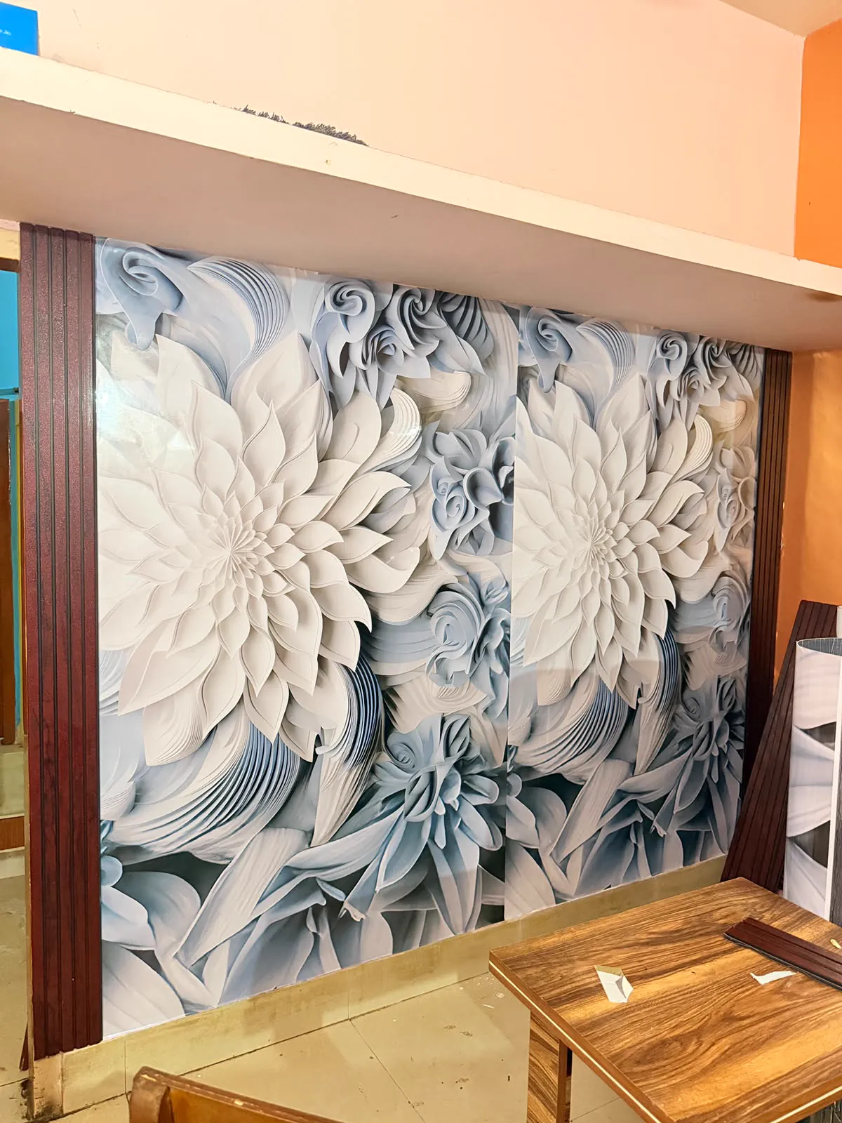 Two drops of a white and pale blue three-dimensional floral mural hung on a wall