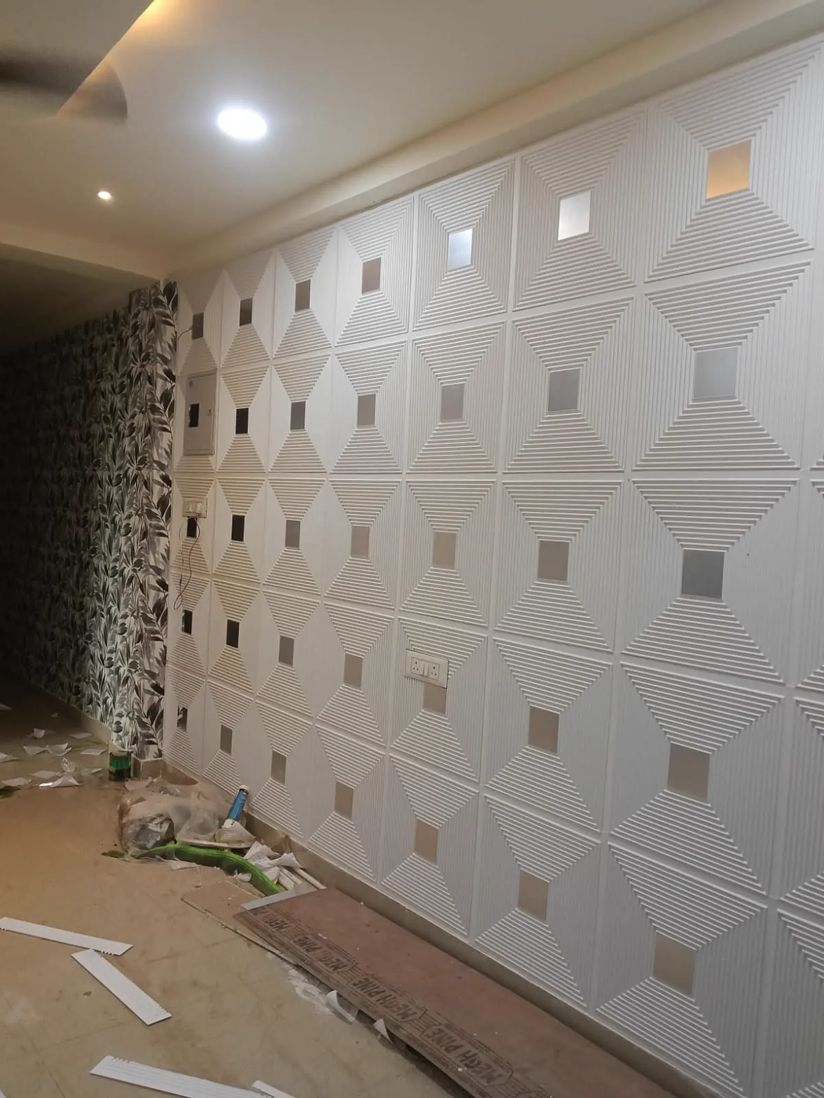 White diamond-relief 3D PVC panels part-way through installation, offcuts on the floor